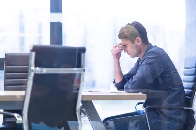 Un tiempo para relajarse Hombre de negocios casual cansado joven que se relaja en el escritorio en su oficina