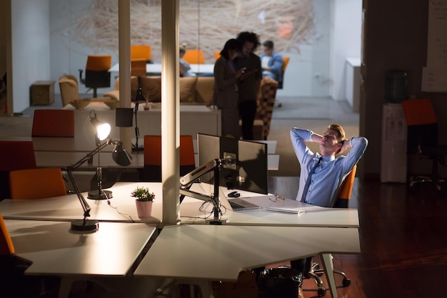 Un tiempo para relajarse. Joven empresario casual cansado relajándose en el escritorio de su oficina nocturna