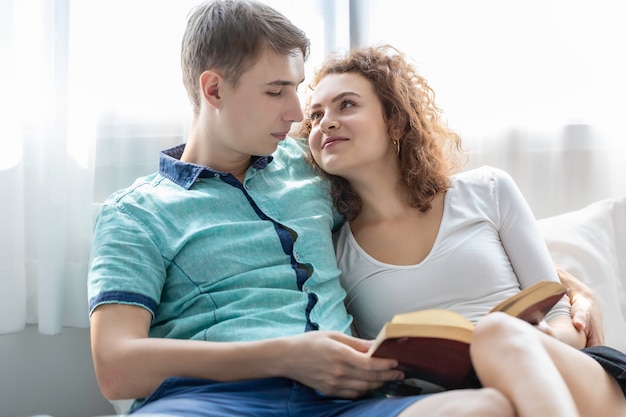 Tiempo romántico. Pareja caucásica abrazo y libro de lectura en la cama.