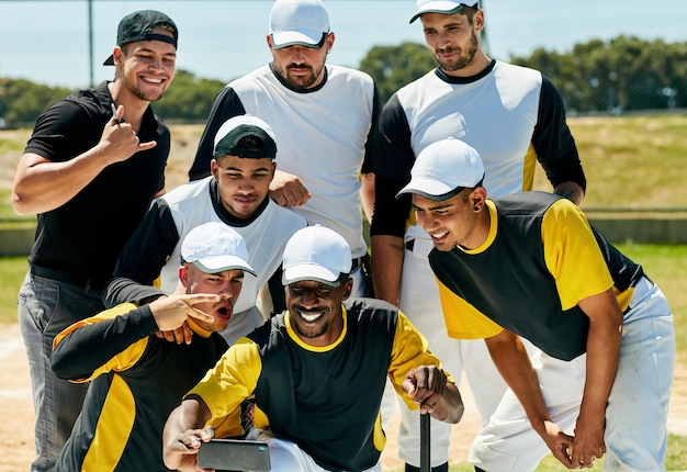 Tiempo de selfie con los ganadores Captura recortada de un equipo de jóvenes jugadores de béisbol haciéndose una selfie juntos mientras están de pie en el campo durante el día