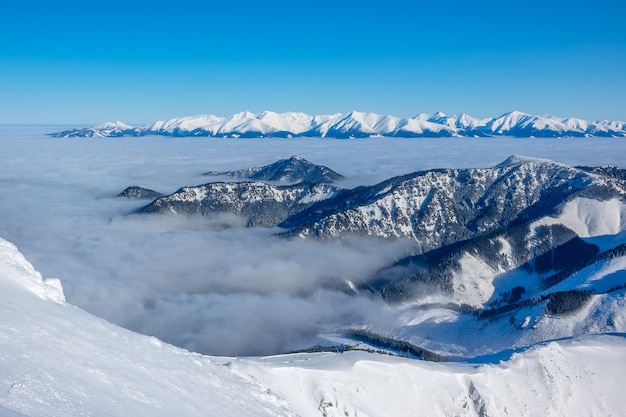 Tiempo soleado y cielo azul. Las cimas de las montañas invernales y la ligera niebla en los valles.