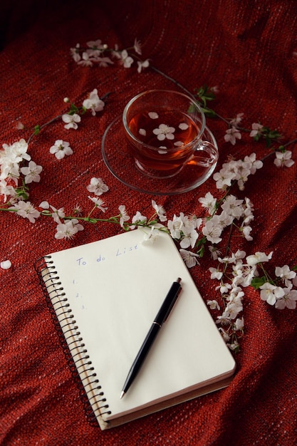 Tiempo para el té bolígrafo de cuaderno vacío y flores de cerezo en la mesa