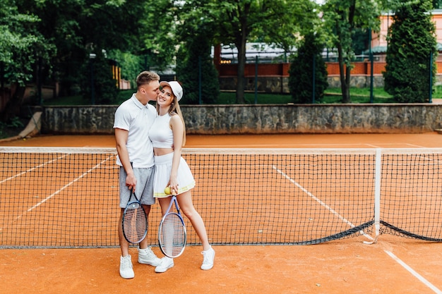 Tiempo de tenis, pareja relajante después de jugar un partido de tenis afuera en verano.