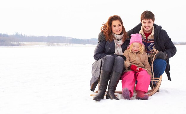 Tiempo de unión en el hielo Dos adolescentes y un niño sentados en un trineo de nieve al aire libre en un fresco día de invierno