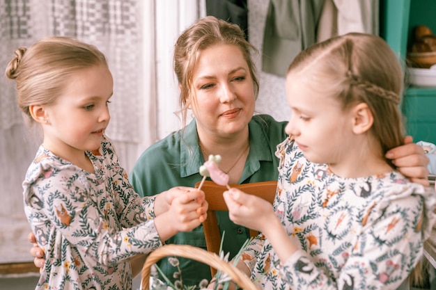 Tiempo de vacaciones de Pascua en la temporada de primavera familia feliz sincero niños pequeños hermanas niñas juntas madre mamá divertirse en casa contactando comunicación y jugando tradición religiosa