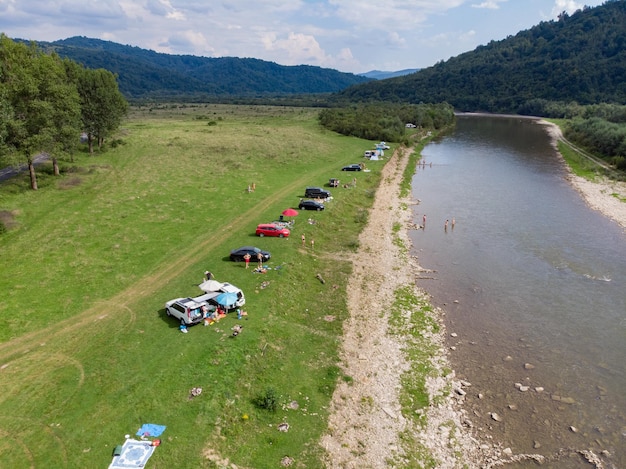 Tienda de campaña con coche cerca de la vista aérea del río de las montañas