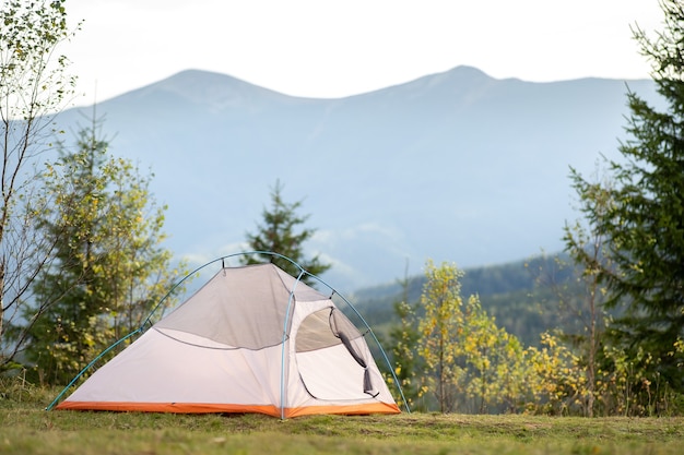 Tienda de campaña de excursionistas vacía de pie en el camping con vistas a los majestuosos picos de alta montaña en la distancia. Camping en la naturaleza salvaje y el concepto de viaje activo.