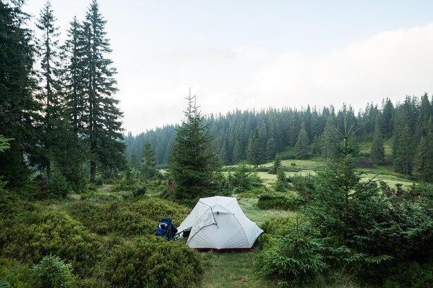 Foto una tienda de campaña en un prado en las montañas para viajes al aire libre