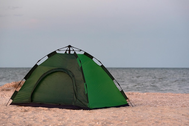Tienda de campaña verde en la playa de arena contra el fondo del mar Camping junto al mar