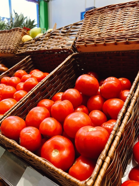 En la tienda de granja ecológica, los tomates maduros rojos están en una canasta a la venta, la tienda ofrece diferentes tipos de tomates