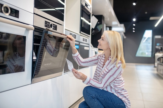 En la tienda. Mujer rubia eligiendo horno en una megatienda