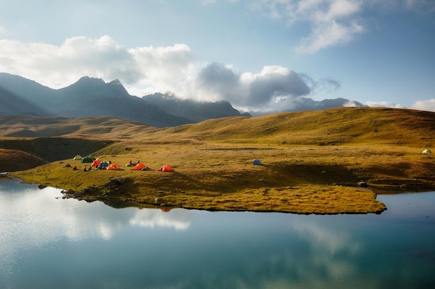 Tienda en la orilla de un lago de montaña enmarcado por montañas rocosas Rusia montañas del Cáucaso Arkhyz