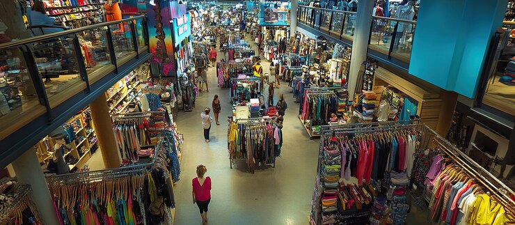 Una tienda de ropa ocupada llena de compradores y mercancías coloridas