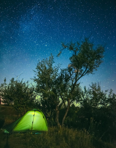 Tienda turística brillante bajo cielo estrellado