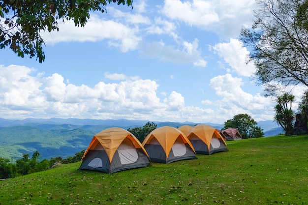 Tiendas de campaña en la cima de la montaña con cielo azul y nubes