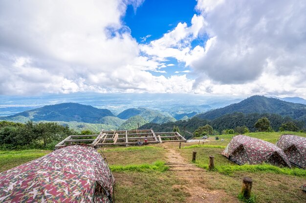 Tiendas en camping entre prado con bello paisaje en las montañas bajo el cielo y clou