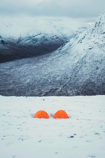 Tiendas naranjas en una montaña nevada