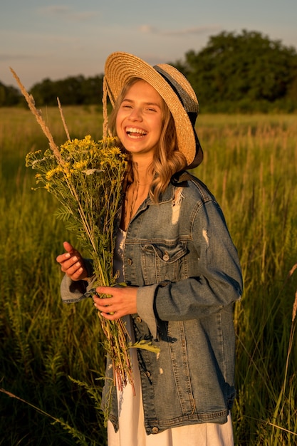 Tiene un ramo de flores silvestres en sus manos. Se relaja en la naturaleza y disfruta de los días cálidos.