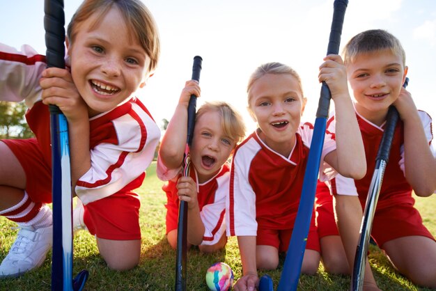 Tienen un fuerte espíritu de equipo Retrato de niños felices jugando hockey sobre césped