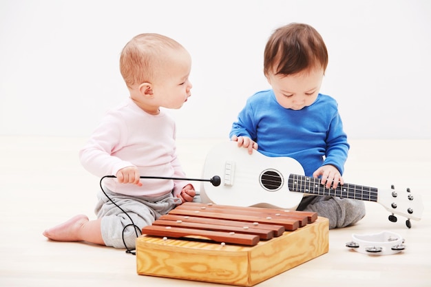 Tienen los ingredientes de una banda exitosa Foto de dos adorables bebés jugando con instrumentos musicales de juguete