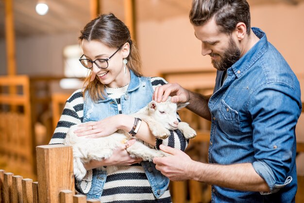 Tierärzte von Mann und Frau kümmern sich in der Scheune um kleine Babyziegen