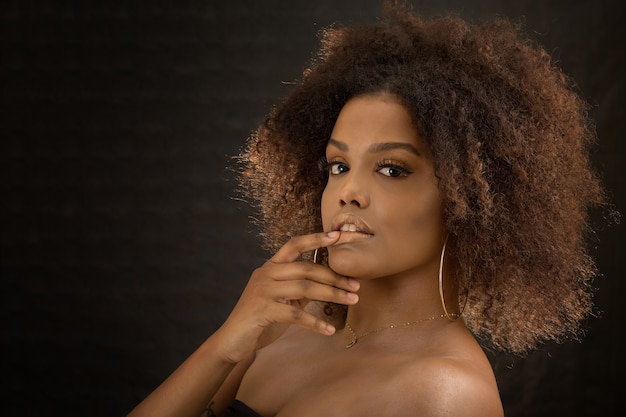 Foto tierna mujer étnica con cabello afro acariciando los labios