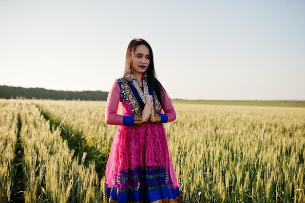 Tierna niña india en sari con maquillaje de labios violetas posó en el campo al atardecer