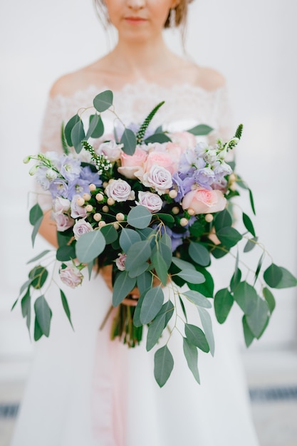 Foto una tierna novia sostiene un ramo de rosas, verónica, delfinio y ramas de eucalipto en sus manos