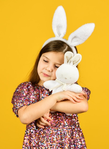 Tierno amor Concepto de primavera Niña pequeña sostiene juguete de liebre Infancia feliz Niño lindo juega con juguete Tienda de juguetes Chica en adorables orejas de conejo divertidas Felices vacaciones de Pascua Preparación de vacaciones de primavera