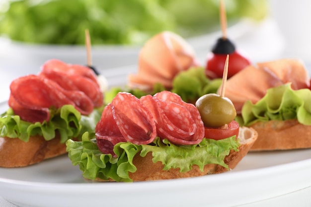 Tiernos canapés de baguette con salami de lechuga de hoja o jamón de Parma tomates mozzarella