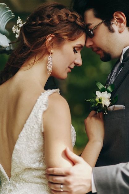 Tiernos toques de una pareja de novios posando en el jardín