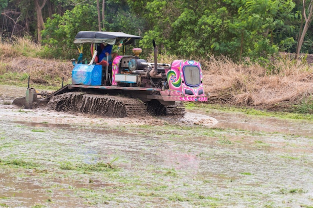 Tierras agrícolas, tractor con arado arando un campo de tierra.