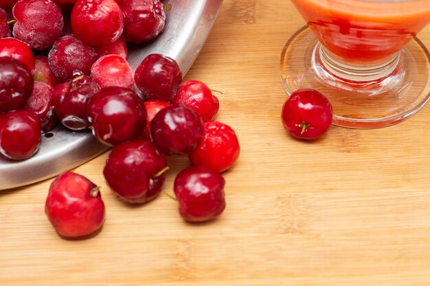 Tigela cheia de acerolas frescas ao lado de suco de acerola