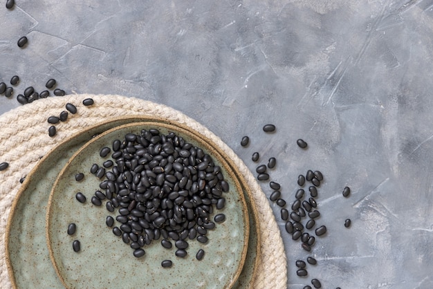 Foto tigela cheia de feijão preto seco na vista superior da mesa cinza com espaço de cópia. alimentação saudável e conceito vegetariano. ingrediente primo tradicional da américa latina