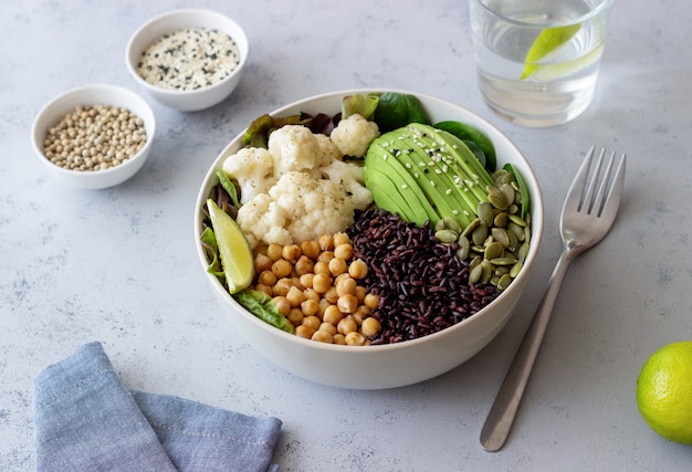 Tigela com abacate, arroz preto, grão de bico, repolho, espinafre e salada. Alimentação saudável. Comida vegetariana.