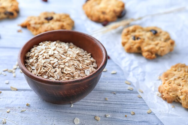 Tigela com aveia e biscoitos deliciosos no fundo de madeira