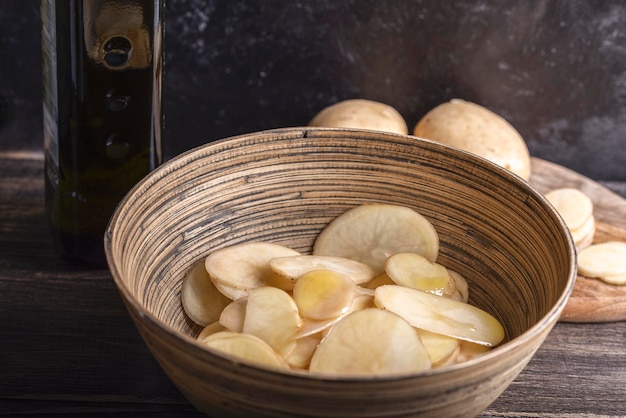 Tigela com batatas cruas fatiadas com óleo