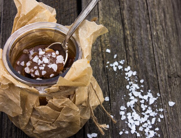 Tigela com caramelo salgado e doces em fundo de madeira, espaço para texto