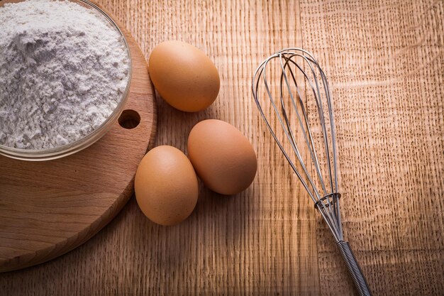 Tigela com corola de ovos de farinha no conceito de comida e bebida de tábua de madeira