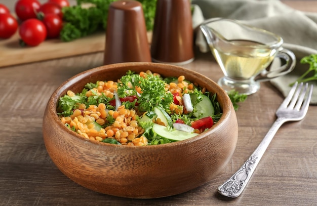 Tigela com deliciosa salada de lentilhas na mesa de madeira