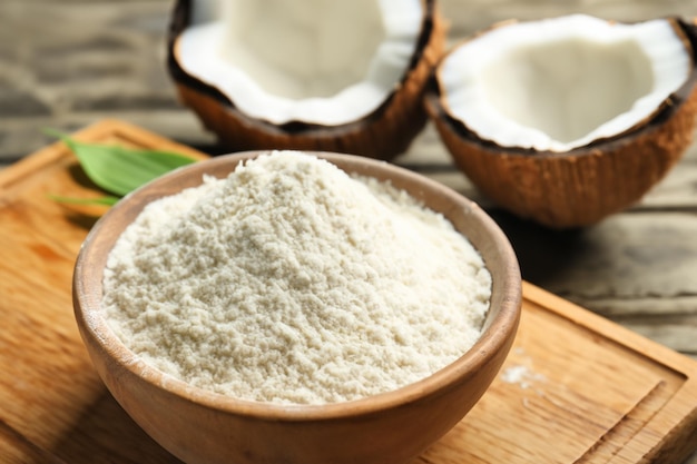 Tigela com farinha de coco na tábua de madeira