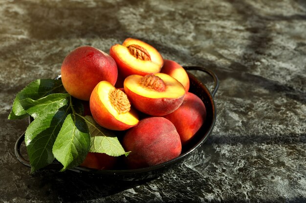 Tigela com frutas de pêssego na mesa preta esfumada