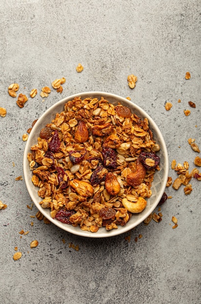 Tigela com granola caseira crocante, granola de cereais matinais saudáveis com aveia, sementes, nozes, frutas vermelhas em um fundo de pedra rústico de cima