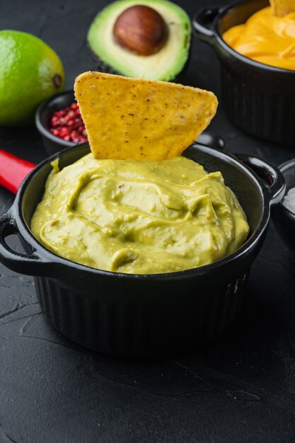 Foto tigela com guacamole de abacate maduro, mesa preta