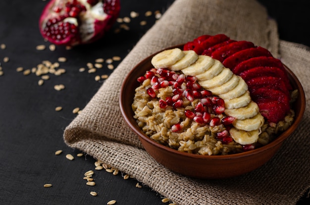 tigela com mingau de aveia, banana, sementes de romã e opuntia cactus fruit