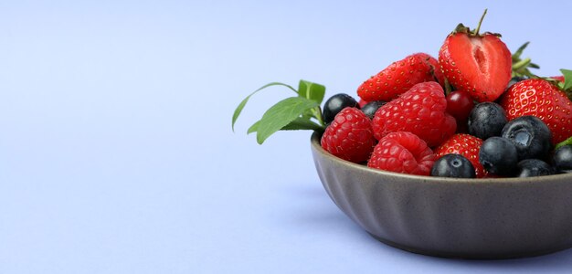 Tigela com mistura de frutas vermelhas em fundo violeta