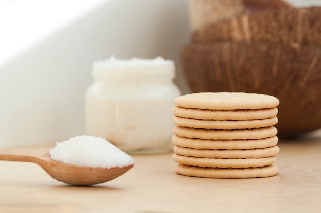 Tigela com óleo de coco e biscoitos em fundo de madeira