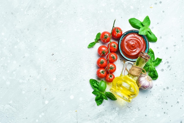 Tigela com pasta de tomate e ingredientes para cozinhar em um fundo de pedra cinza Ketchup Vista superior Espaço livre para texto