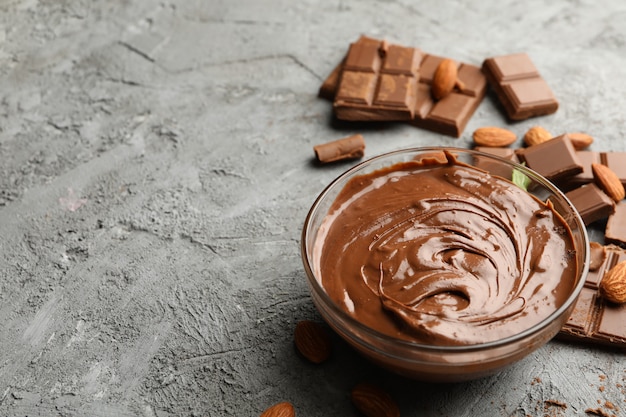 Tigela com pedaços de chocolate e chocolate no fundo cinza