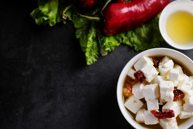 Tigela com pedaços de queijo feta e tomates secos e óleo, vista superior com copyspace